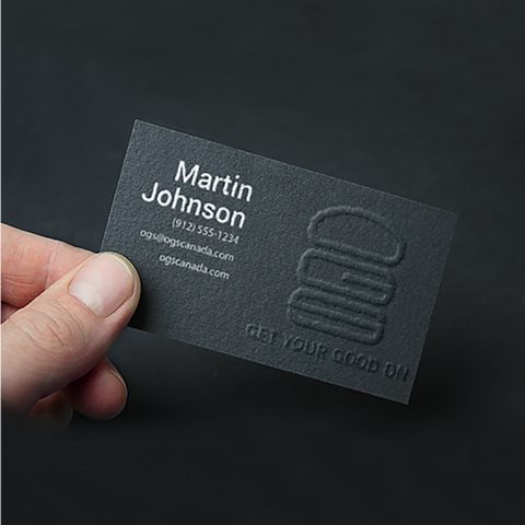 A black embossed business card held in a hand