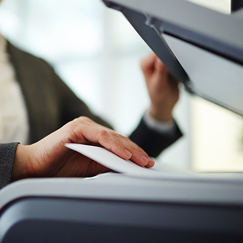 A hand lifting the lid of a photocopier